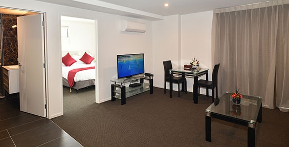 spacious lounge with comfortable couch, dining table and flatscreen smart TV